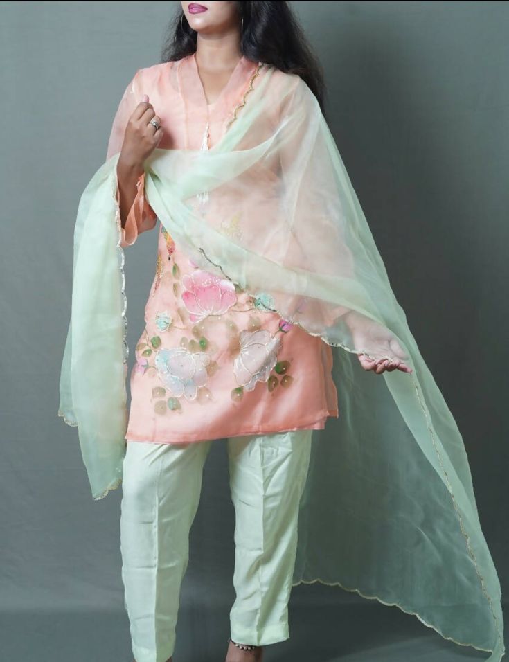 3 pc suit consisting of peach kurta, light green pant, and light green chiffon dupatta Delicately hand painted organza kurta with beautifully designed floral patterns on daman and sleeves Kurta styled with three quarter sleeves and heavy tassel hanging pearl lace on neck Duppata enhanced with curved golden pippin on all borders Number of components sold: 4 (Kurta comes with inner) Measurement in the size guide are all body measurements Spring Green Traditional Wear With Gota Work, Green Traditional Wear With Gota Work For Spring, Spring Green Sets With Gota Work, Spring Anarkali Tissue Silk Kurta, Spring Silk Sharara With Dupatta, Spring Semi-stitched Salwar Kameez With Gota Work, Semi-stitched Salwar Kameez With Gota Work For Spring, Spring Chanderi Sharara, Spring Silk Traditional Wear With Sheer Dupatta