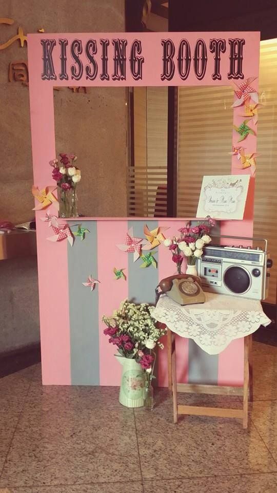 a pink and blue booth with flowers on the table next to an old fashioned washing machine