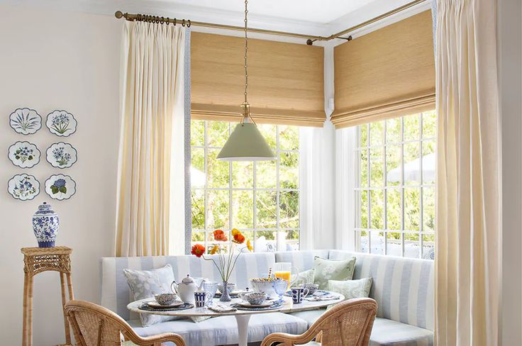 a dining room table and chairs with plates on the table in front of them, next to a bay window