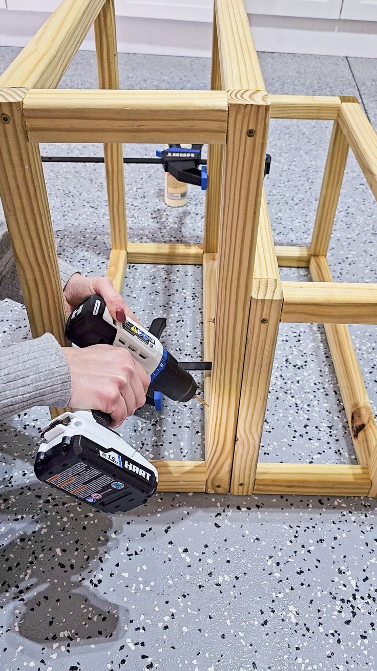 a person using a power drill to attach wood frames