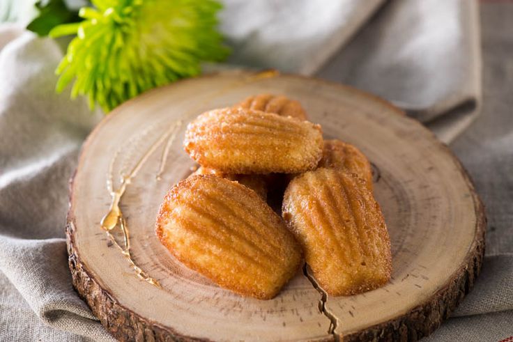 three sugared donuts sitting on top of a wooden plate next to a green plant