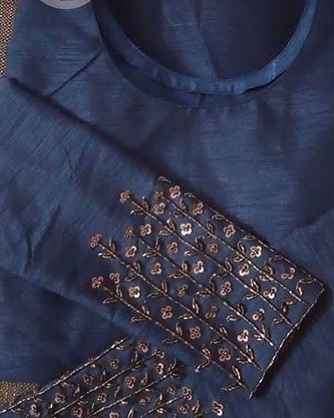 a blue shirt with gold embellishments on the front and back, sitting on a table