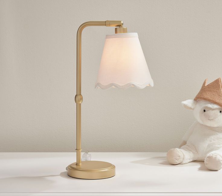 a stuffed animal sitting next to a lamp on a white table with a beige shade