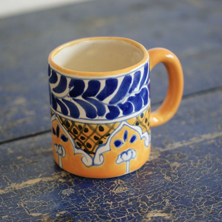 a blue and yellow coffee cup sitting on top of a wooden table