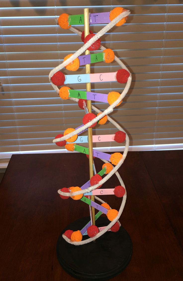 a model of a structure made out of colored pencils on a wooden table with blinds in the background