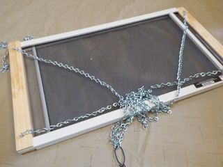 a window with chains attached to it on the ground in front of a wall mounted screen