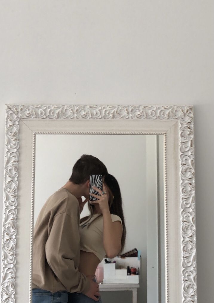 a man and woman standing in front of a mirror