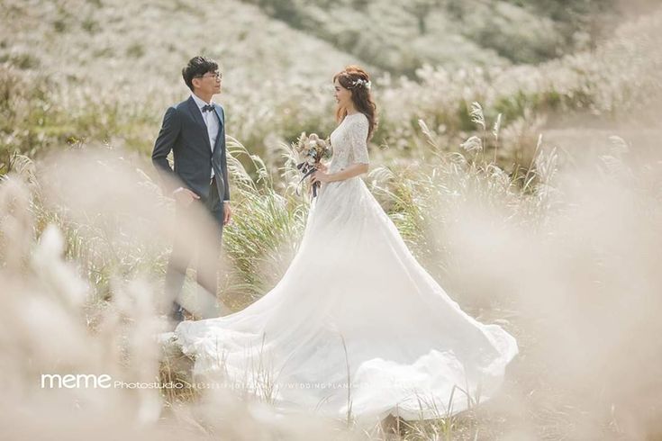 a bride and groom standing in tall grass