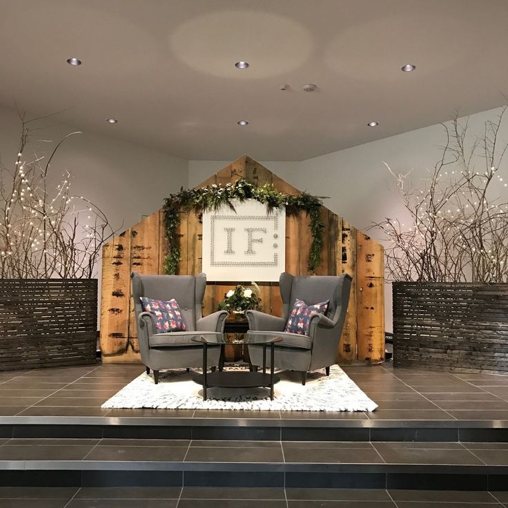 two chairs and a table in front of a wooden wall with plants growing on it