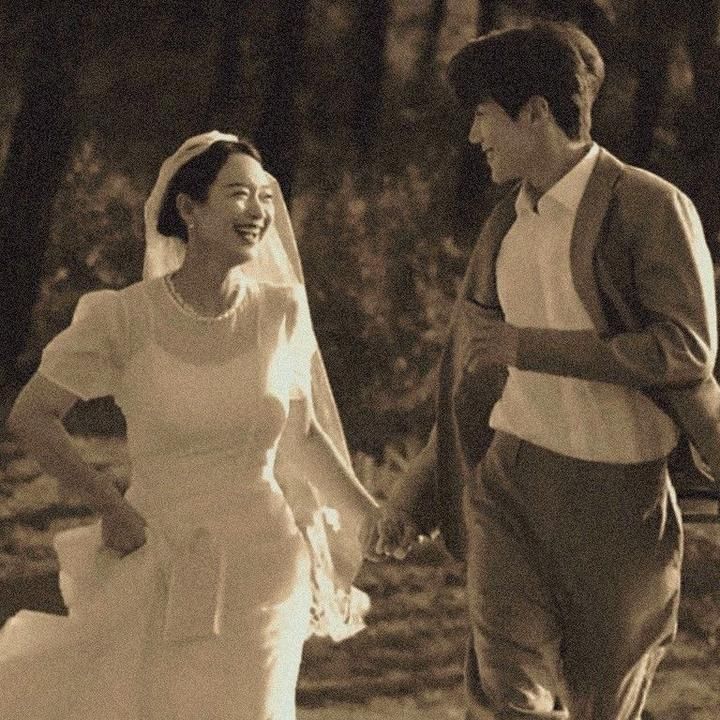 an old photo of a bride and groom walking through the woods holding hands with each other