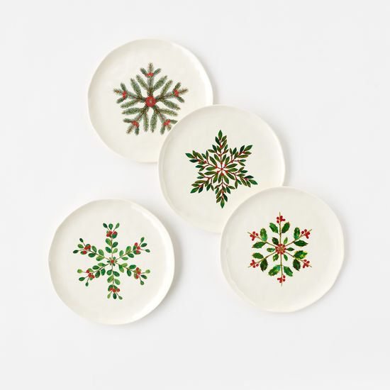 three white plates with green and red designs on the rims, each decorated with holly