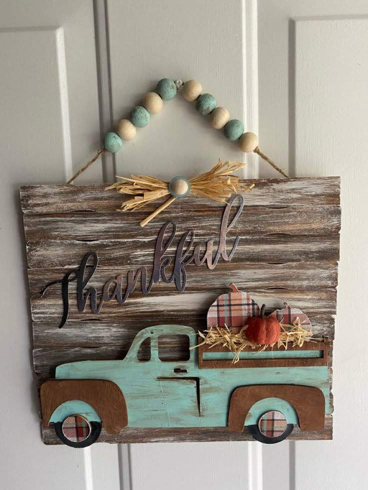 a wooden sign with a truck and pumpkins hanging from it's front door