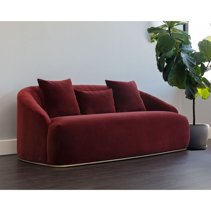 a red couch sitting next to a potted plant