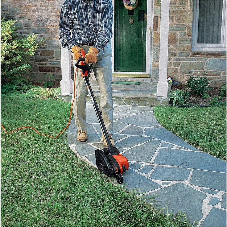 a man is standing in front of his house with a lawn mower