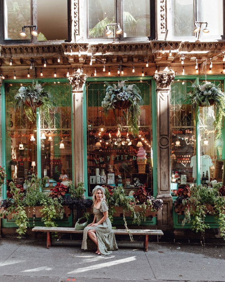 a woman sitting on a bench in front of a flower shop