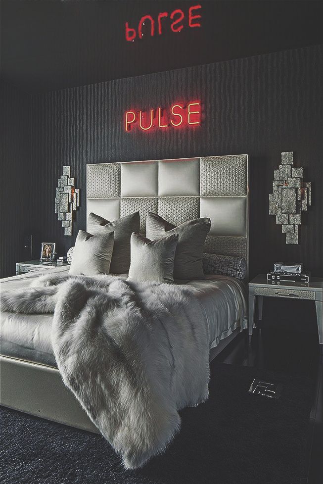 a bedroom with black walls and white fur on the bed, along with a neon sign that reads pure