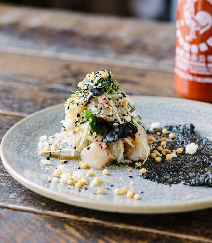 a white plate topped with food on top of a wooden table next to a bottle