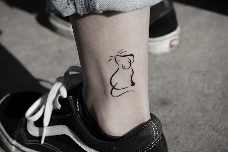 a small tattoo on the ankle of a woman's foot, with a mouse