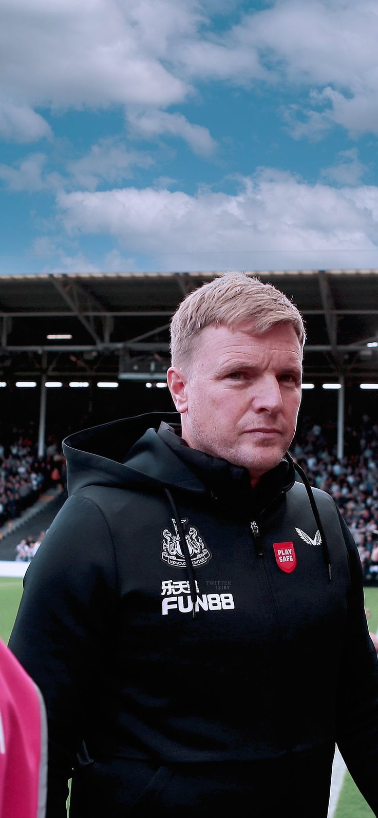 a man standing on top of a soccer field wearing a black hoodie and looking off into the distance