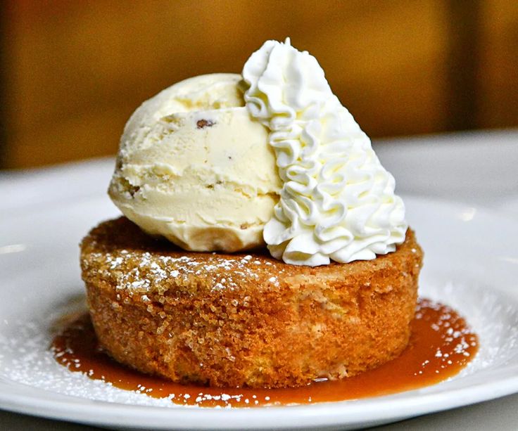 a piece of cake topped with whipped cream and caramel sauce on a white plate