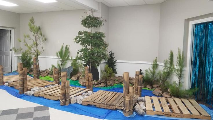 an indoor play area with wooden structures and plants on the ground, along with blue tarps