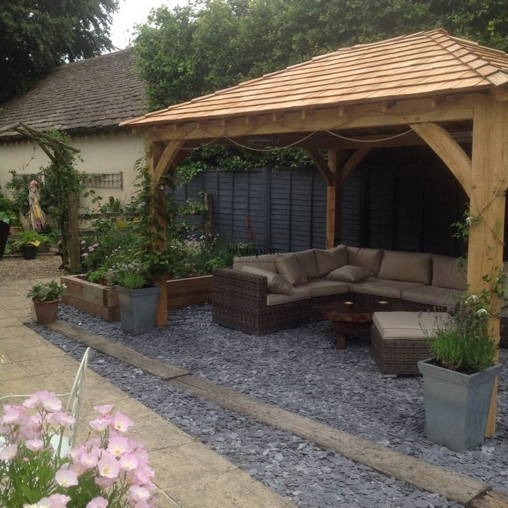 an outdoor living area with couches and potted plants on the side of it