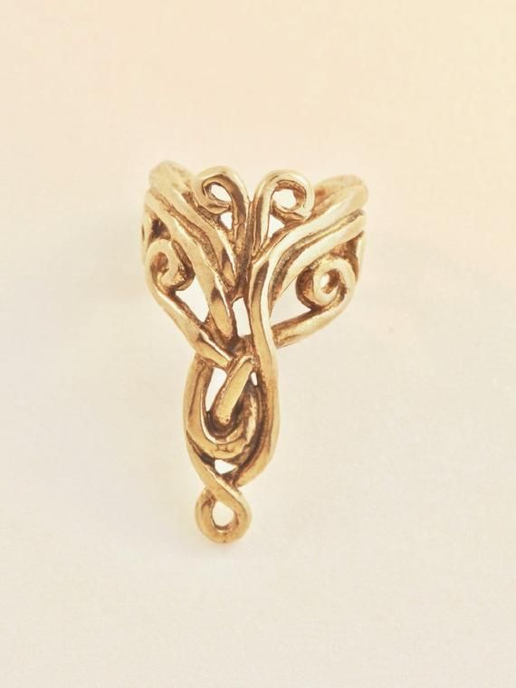 The intricate design of this 14K gold Arabesque Ear Cuff is both classic and exotic. The Arabesque Ear Cuff is 7/8" long, comfortable and easy to wear and it fits both the left and the right ears.  Diamond not included.  Our ear cuffs require no piercings. Starting near the top of the ear, simply slide the cuff down along the edge of the ear's cartilage. If minor adjustments are needed, you may gently open or close the opening of the ear cuff to accommodate the thickness of your ear using a pair Elegant Yellow Gold Brass Ear Cuff, Yellow Gold Brass Ear Cuff, Unique Gold Brass Ear Cuff, Unique Spiral Yellow Gold Jewelry, Unique Yellow Gold Spiral Jewelry, Adjustable 14k Gold Ear Cuff, Elegant Spiral Jewelry With Unique Design, Elegant Adjustable 14k Gold Ear Cuff, Unique Gold Swirl Jewelry