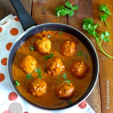 some meatballs and sauce in a pan on a table with parsley sprigs