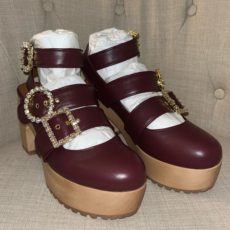 New!! Never Worn Authentic Autumn Adeigbo Clogs - Currently At Nordstrom For $780. Featuring A Trio Of Straps Detailed With Signature Mixed-Match Crystal Buckles, These Wooden Clogs Are Crafted Of Burgundy Red Leather. The Closed-Toe Style Sits On A 1.75" Platform That Makes The 4" Heel Comfortably Walkable. They're Finished With A Vibram Rubber Sole For Great Traction And Shock-Absorbing Support. * Produced In Limited Quantities. * 4" Wood Heel. 1.75" Wood Platform. (Size Eu 40/ Us 9) * Leather Party Platform Clogs With Round Toe, Party Clogs With Wooden Block Heel, Leather Clogs With Round Toe For Party, Leather Round Toe Clogs For Party, Party Leather Clogs With Round Toe, Leather Party Clogs With Round Toe, Autumn Adeigbo, Red Clogs, Wooden Clogs