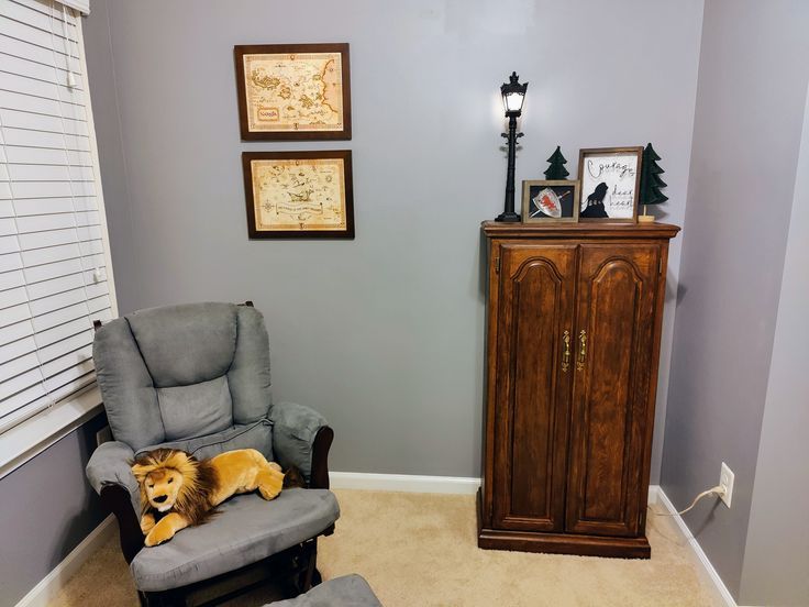 a dog laying on top of a chair in a living room next to a dresser