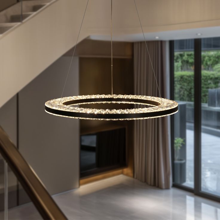 a circular chandelier hanging from the ceiling in a living room next to a staircase