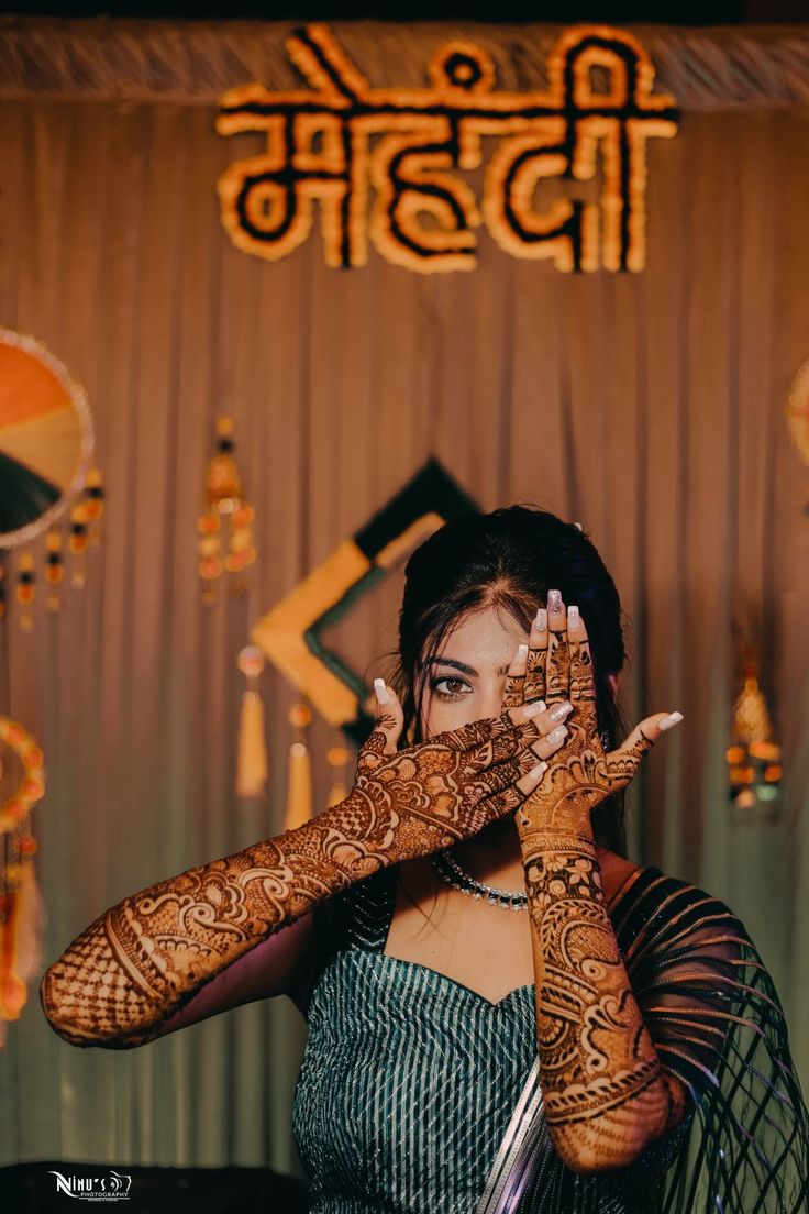 a woman is holding her hands up to her face with hendi tattoos on it