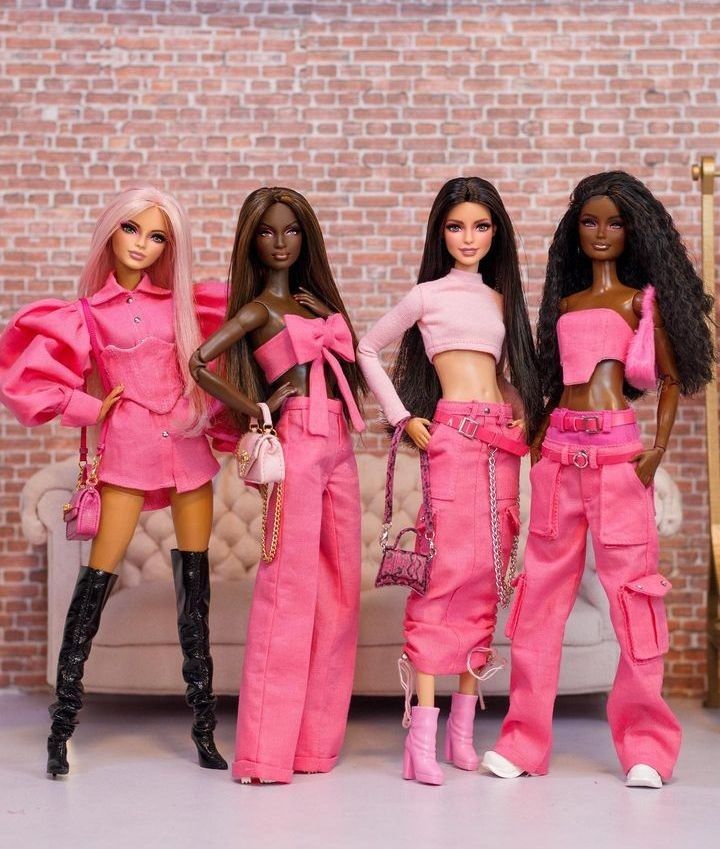 three barbie dolls standing next to each other in front of a couch and brick wall