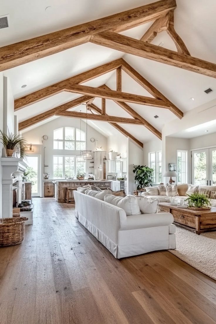 a large living room with wooden beams and white couches in front of a fireplace