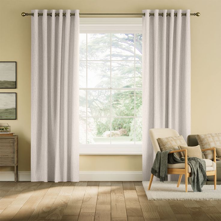 a living room scene with focus on the curtains and chair in front of the window