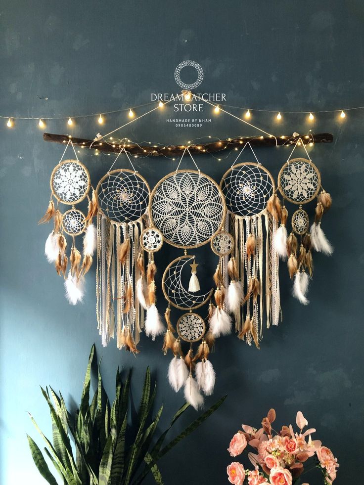 a wall hanging with dream catchers and lights on it's side next to a potted plant