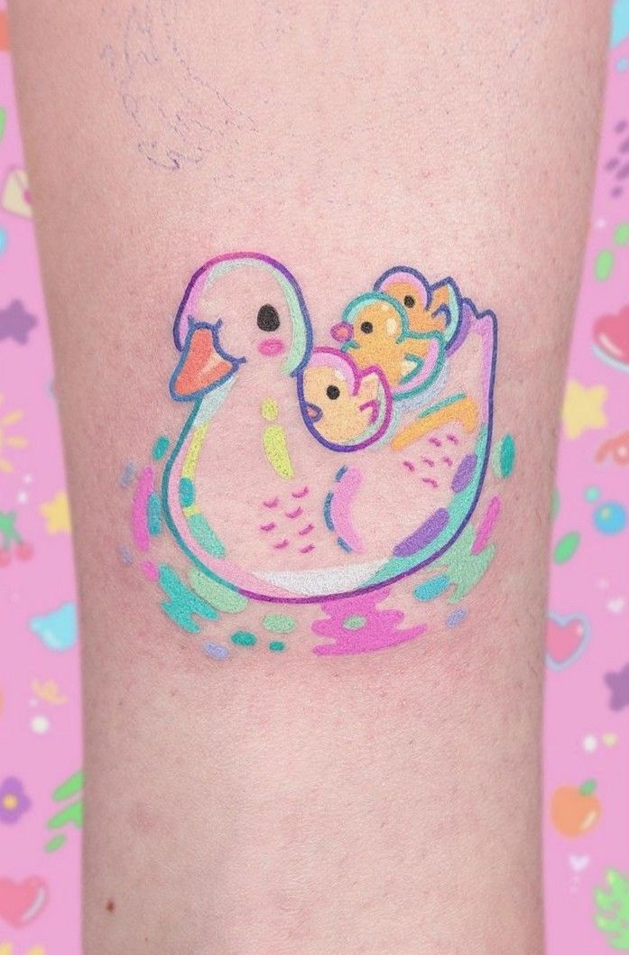 a close up of a person's leg with a duck and baby on it