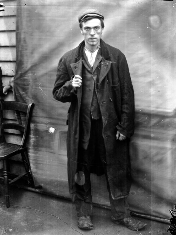 an old black and white photo of a man standing next to a chair