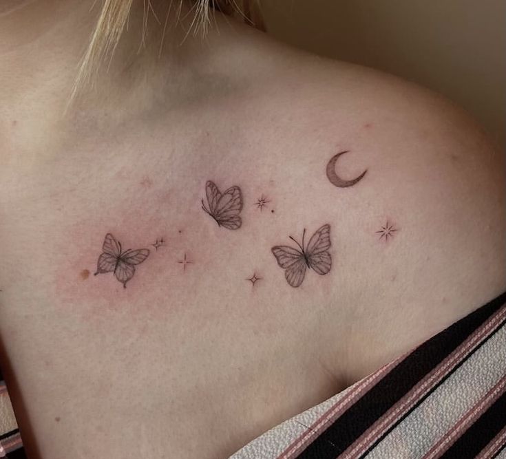 a woman's chest with three butterflies and a crescent moon