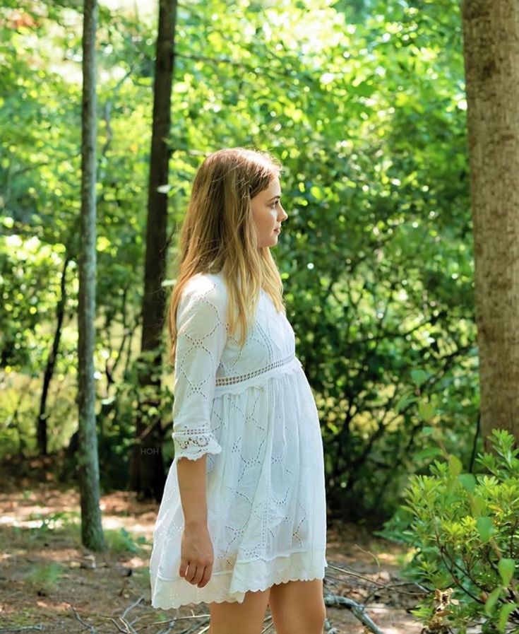 a woman in white is walking through the woods