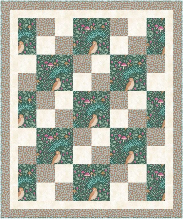 a green and white quilt with two birds on the tree branches in front of it