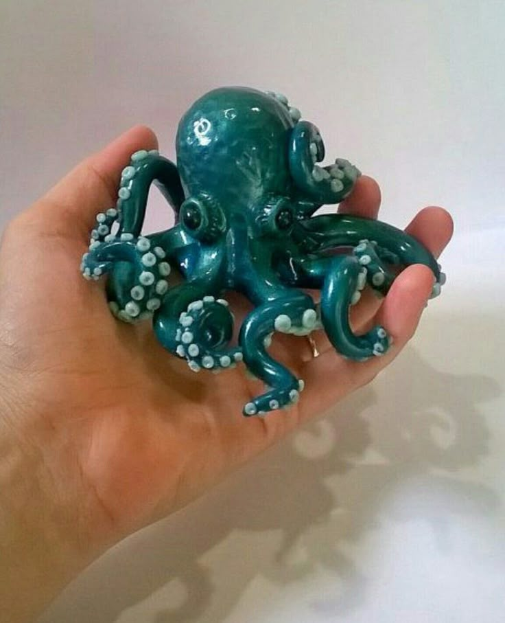 an octopus figurine is held up in the palm of someone's hand