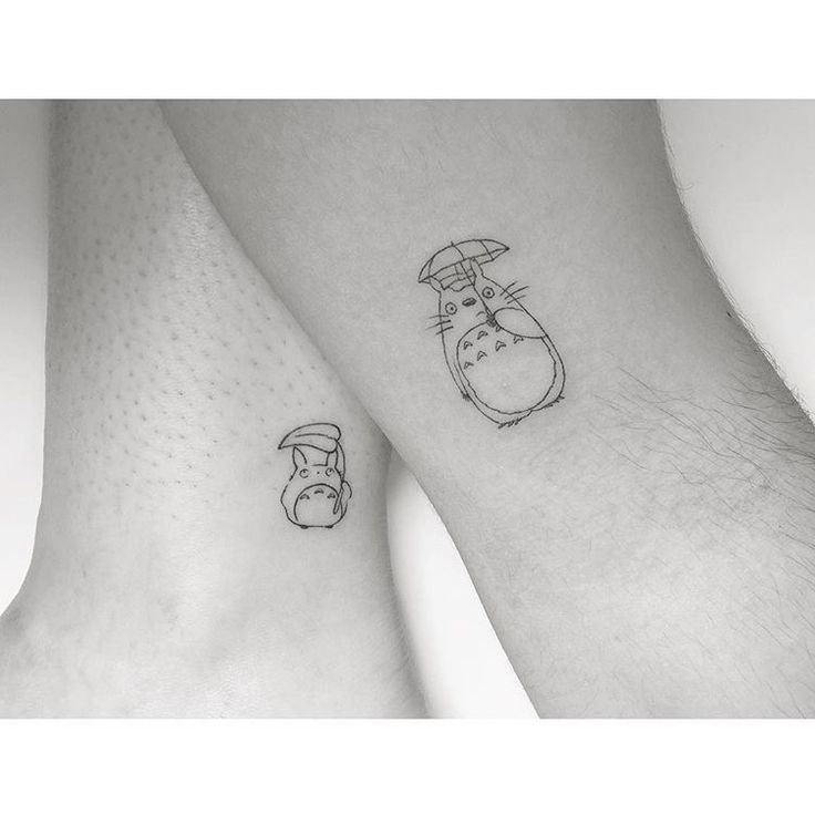 two people's legs with tattoos on them, one has a totoro and the other has an umbrella