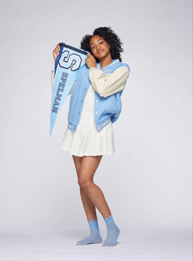 a young woman holding up a blue and white jacket with the number 32 on it