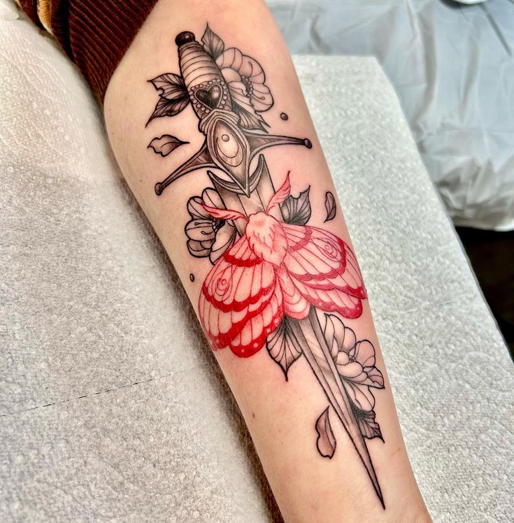 a woman with a tattoo on her arm holding a knife and flower arrangement in front of her leg