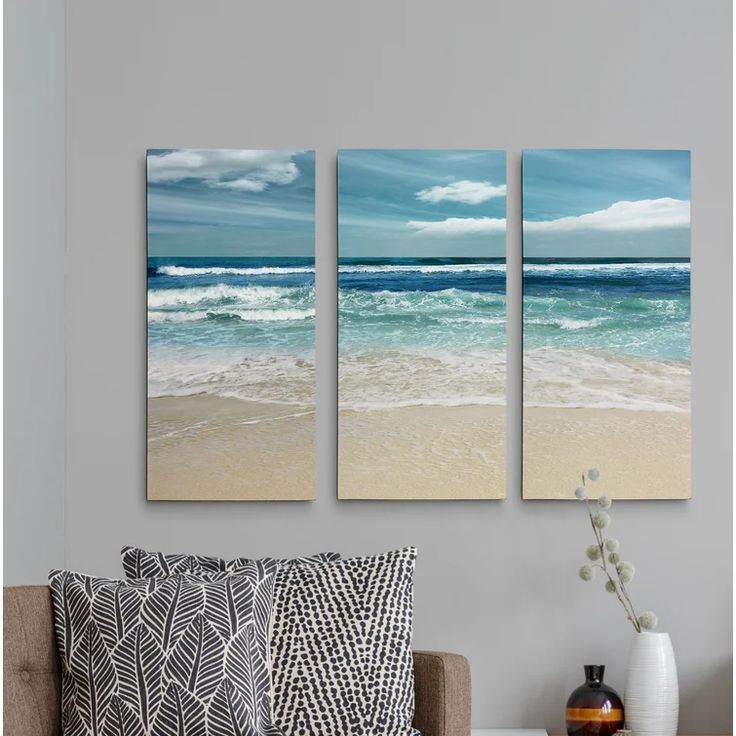 three canvases hanging on the wall above a couch in front of a coffee table