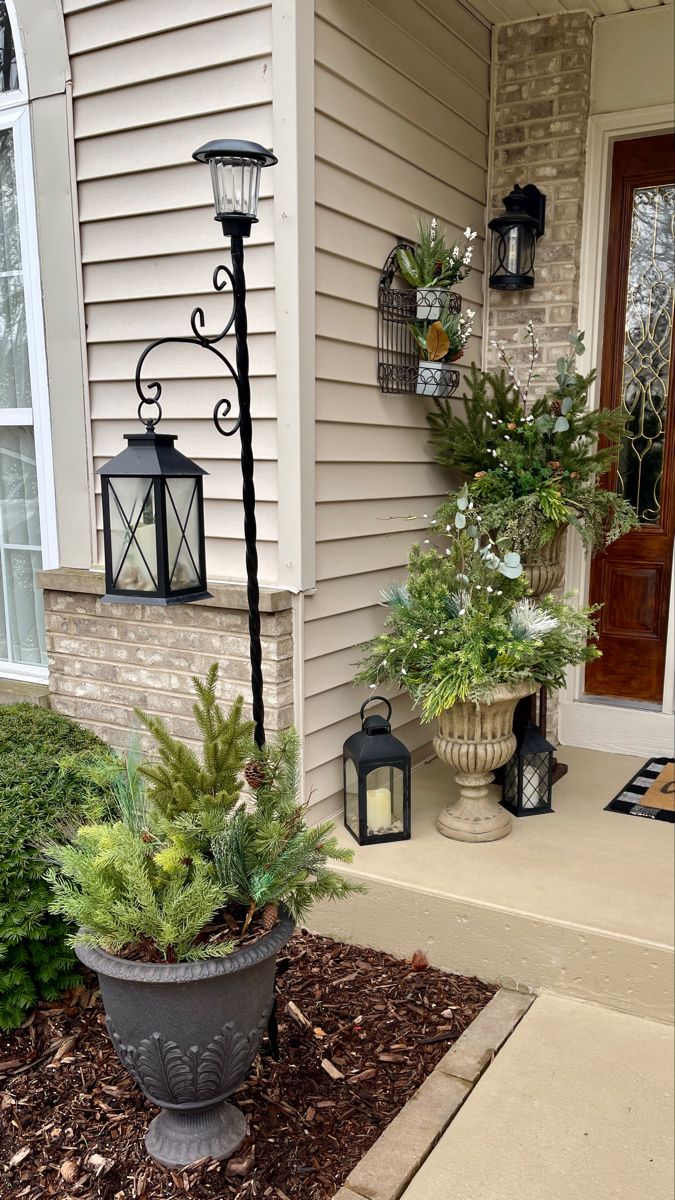 the front porch is decorated with potted plants and hanging lantern lights on either side