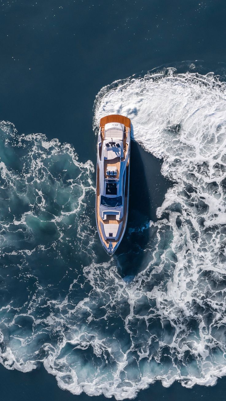 an aerial view of a small boat in the middle of the ocean with foamy water around it