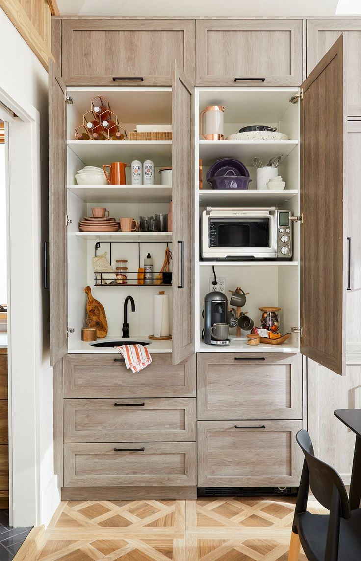 an open cabinet in the middle of a kitchen with lots of counter space and appliances