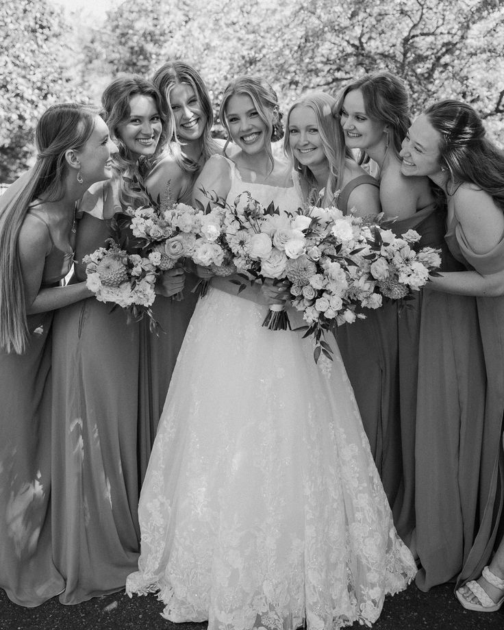 a group of women standing next to each other in front of a tree with flowers